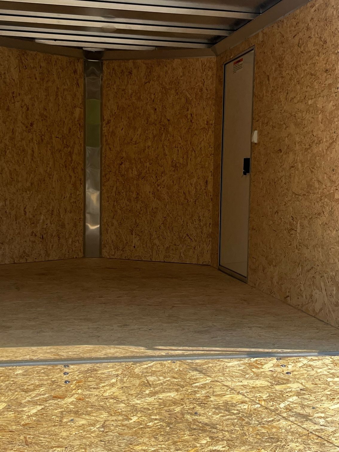 A large empty room with wooden walls and a door.