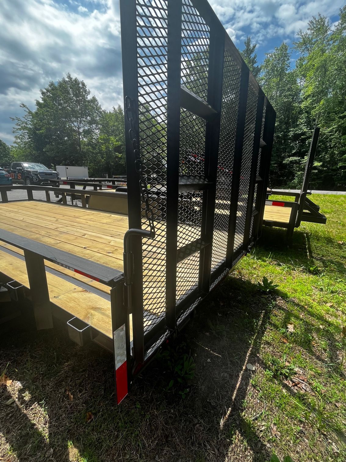 A trailer is parked in the grass next to a fence.