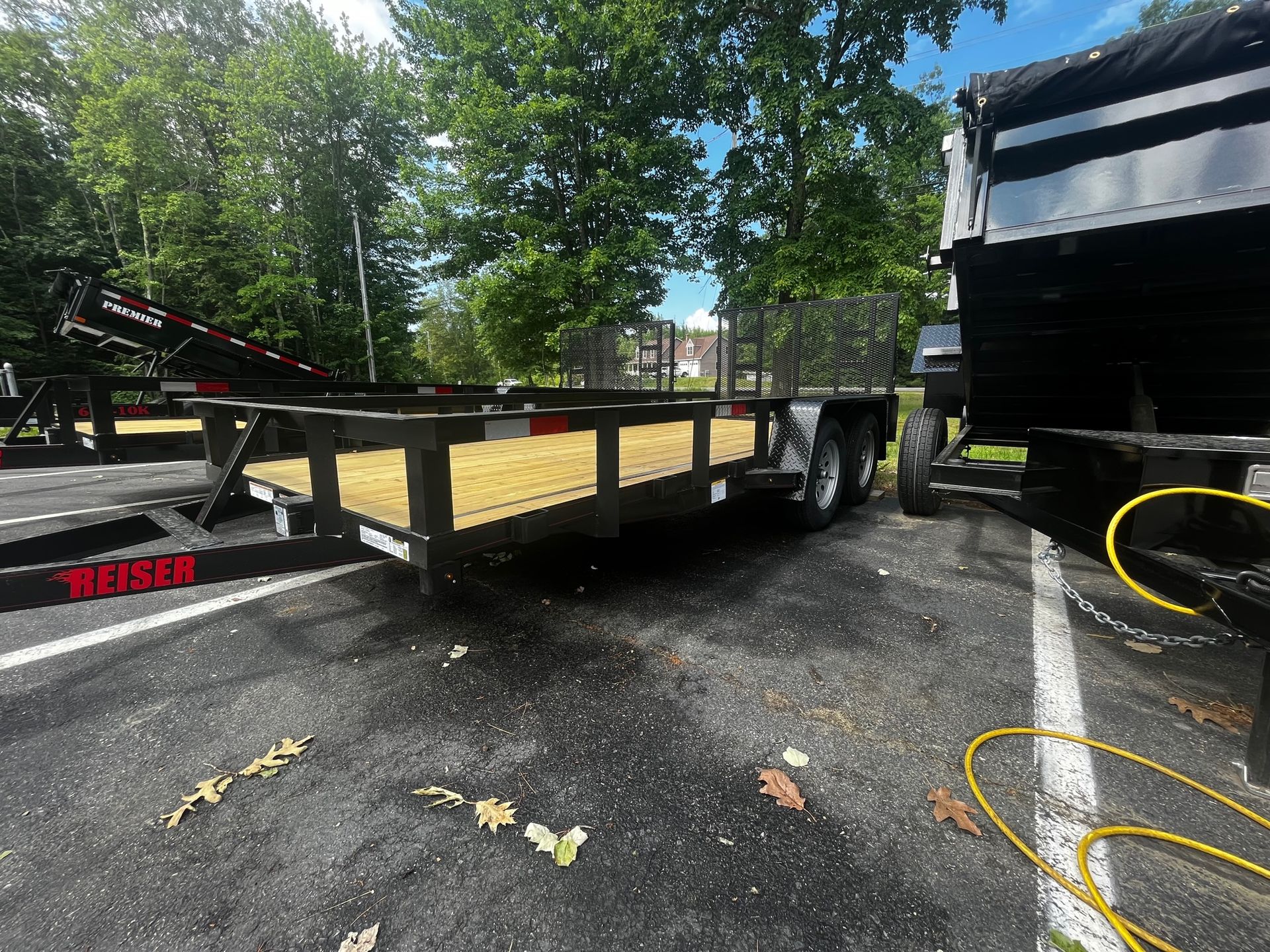 A trailer is parked in a parking lot next to a dump truck.