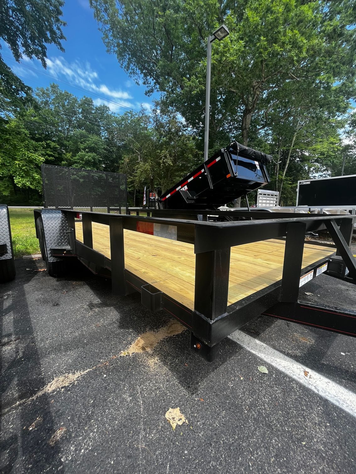 A trailer is parked in a parking lot with trees in the background.