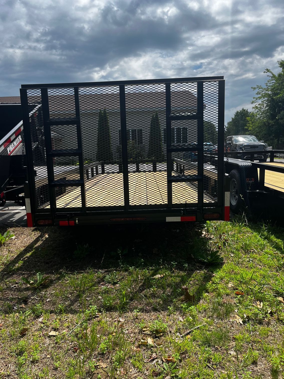 A trailer is parked in a grassy field next to a house.