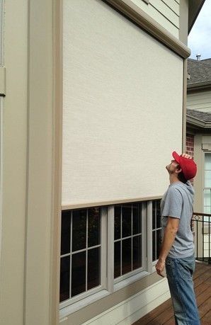 A man is looking up at a window with a solar screen on it