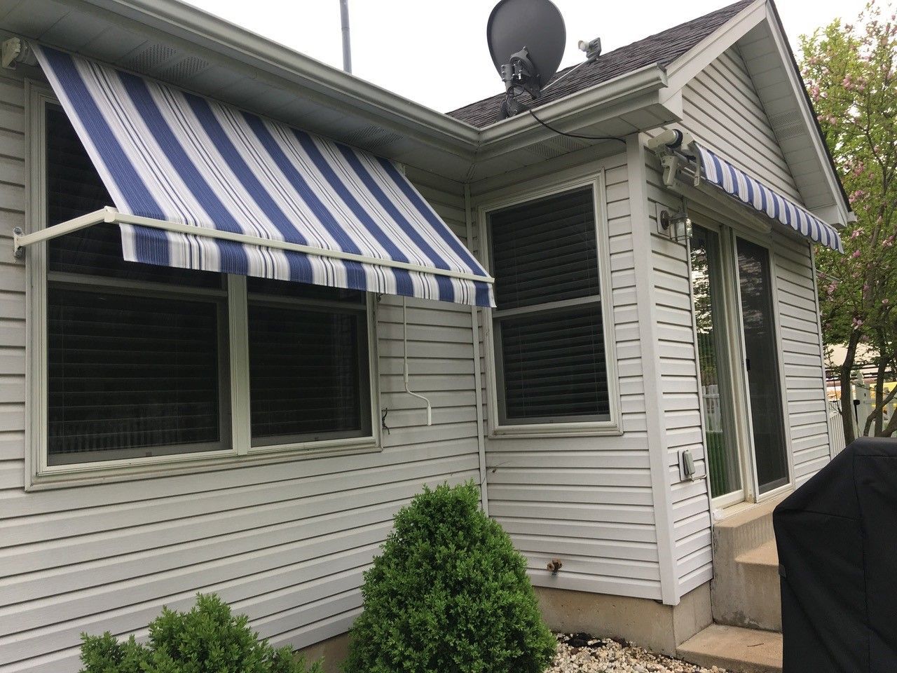 A white house with a blue and white striped awning on the side of it