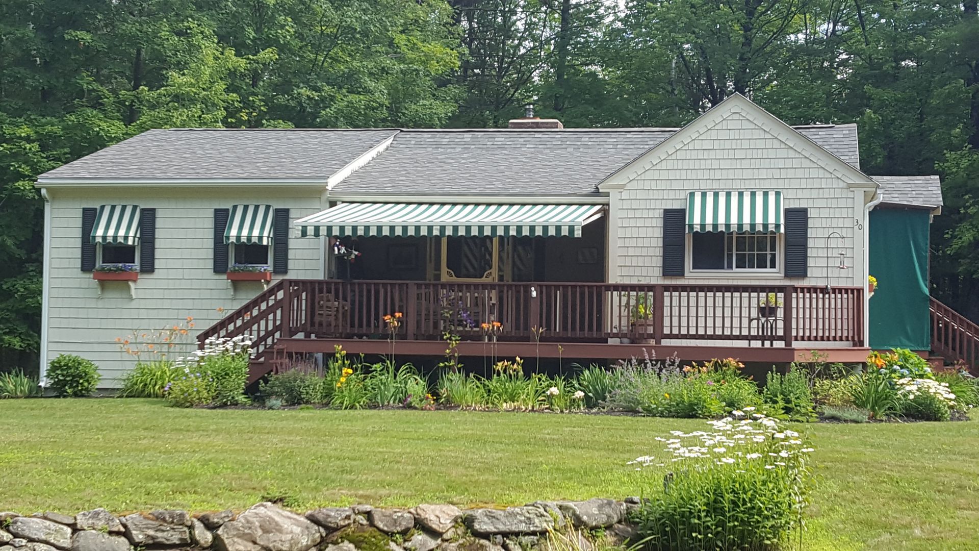 A white house with a green awning on the porch.