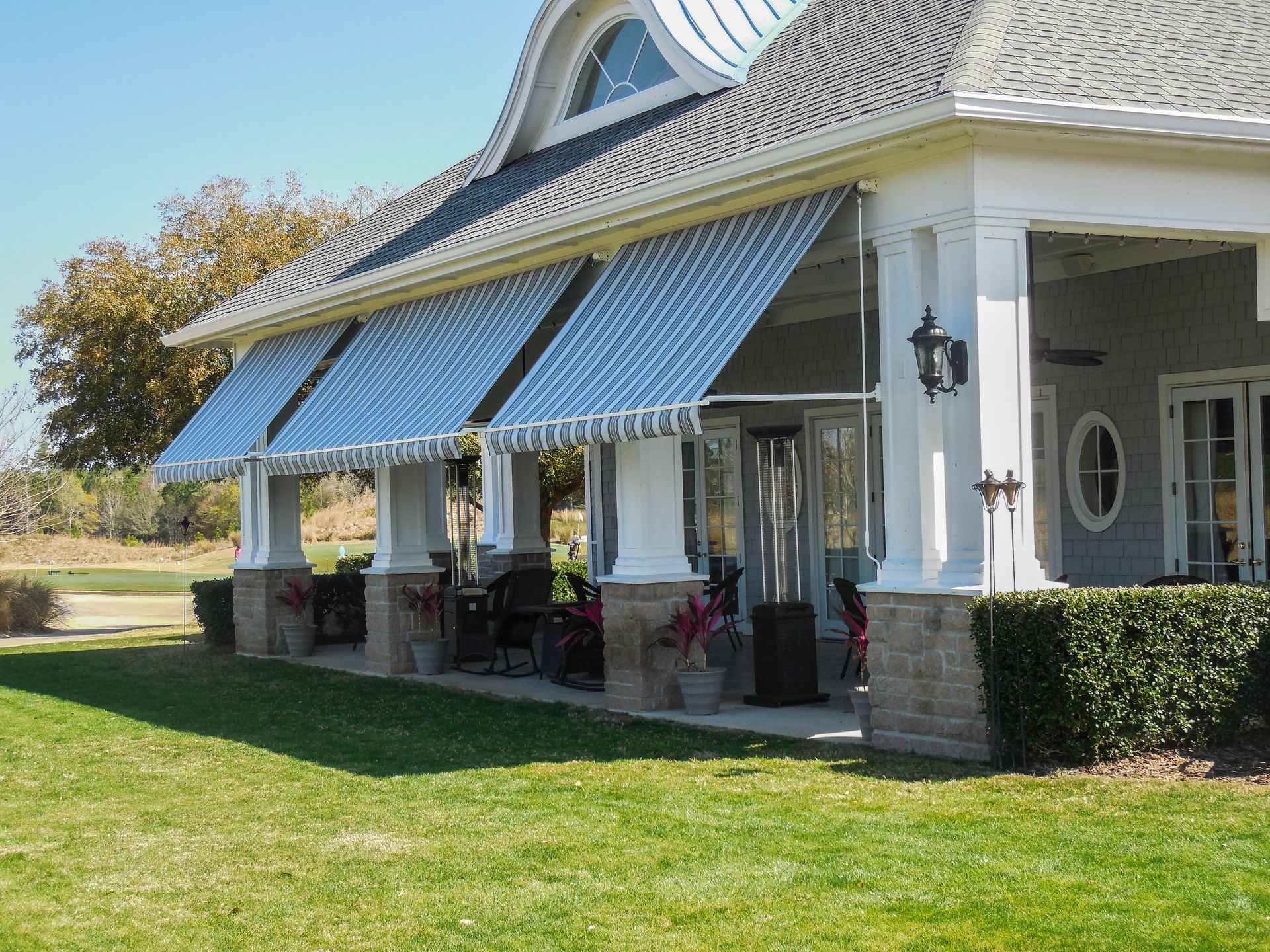 A large house with a porch and awnings on it.