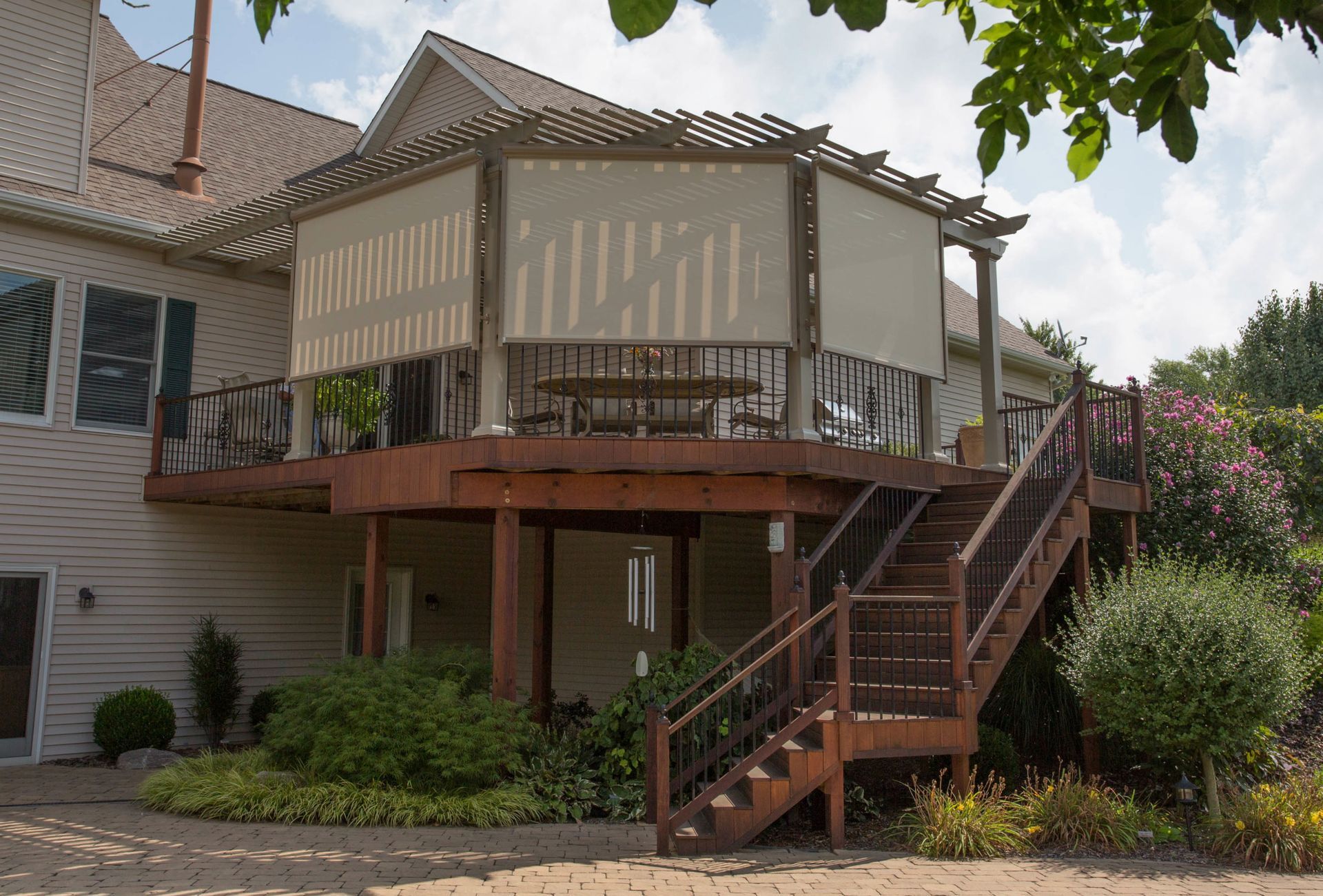 The back of a house with a large deck and stairs leading up to it.