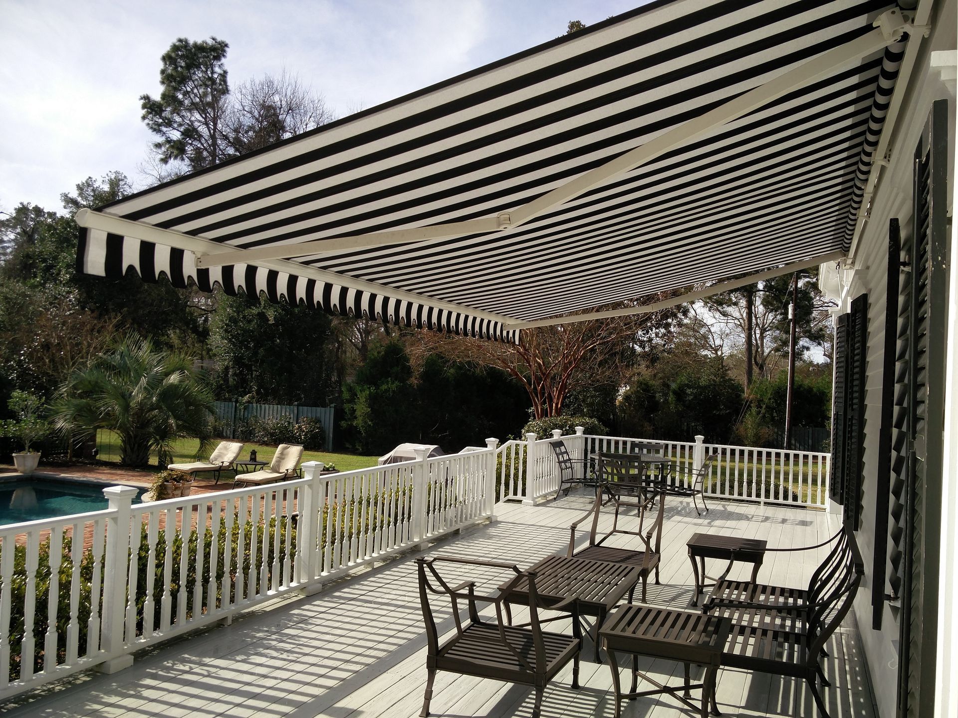 A black and white striped awning over a deck with a table and chairs.