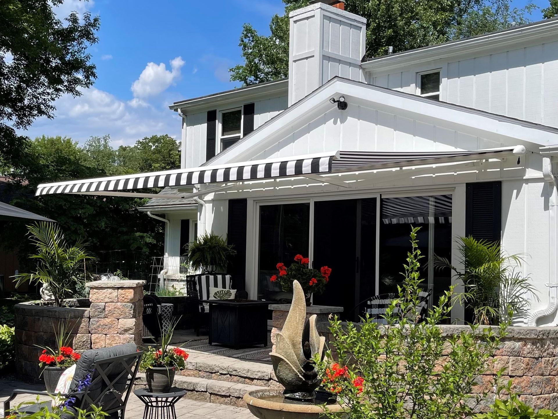 A white house with a black and white awning on the patio.