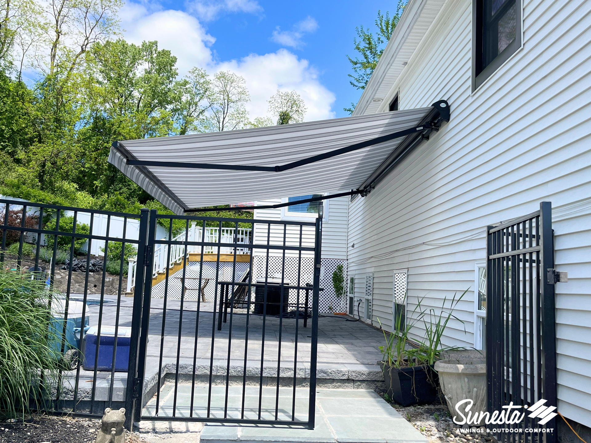 A white house with a black gate and an awning on the side of it.