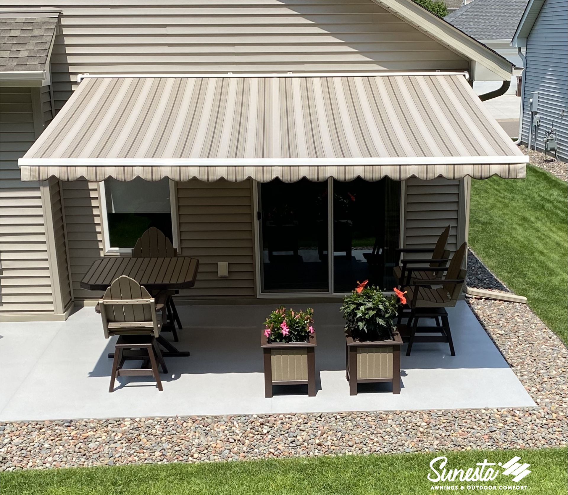 A patio with tables and chairs under a striped awning.