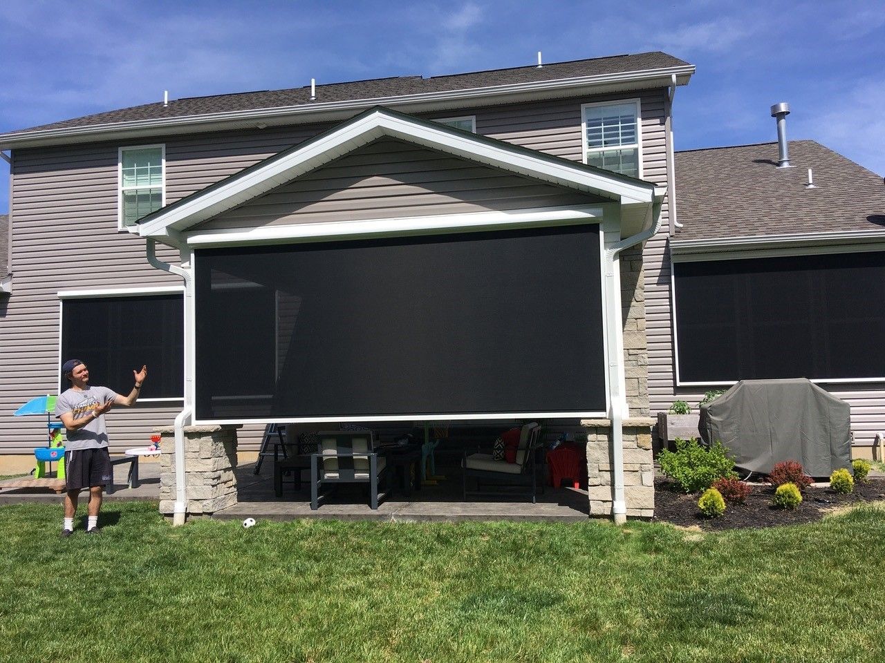 A man is standing in front of a house with a solar screened porch