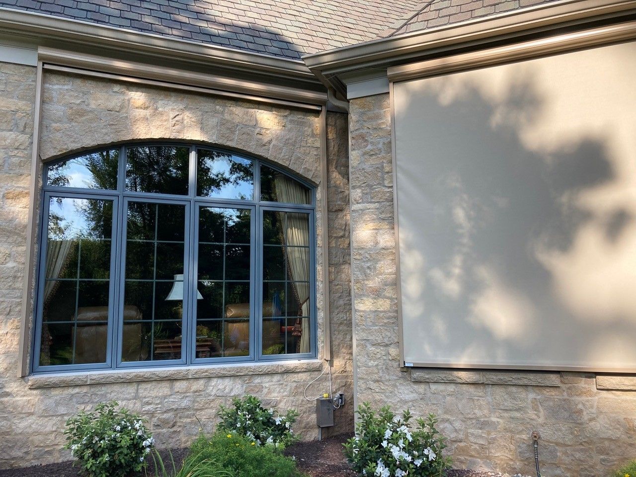 A house with a large window and a solar screen on the side of it