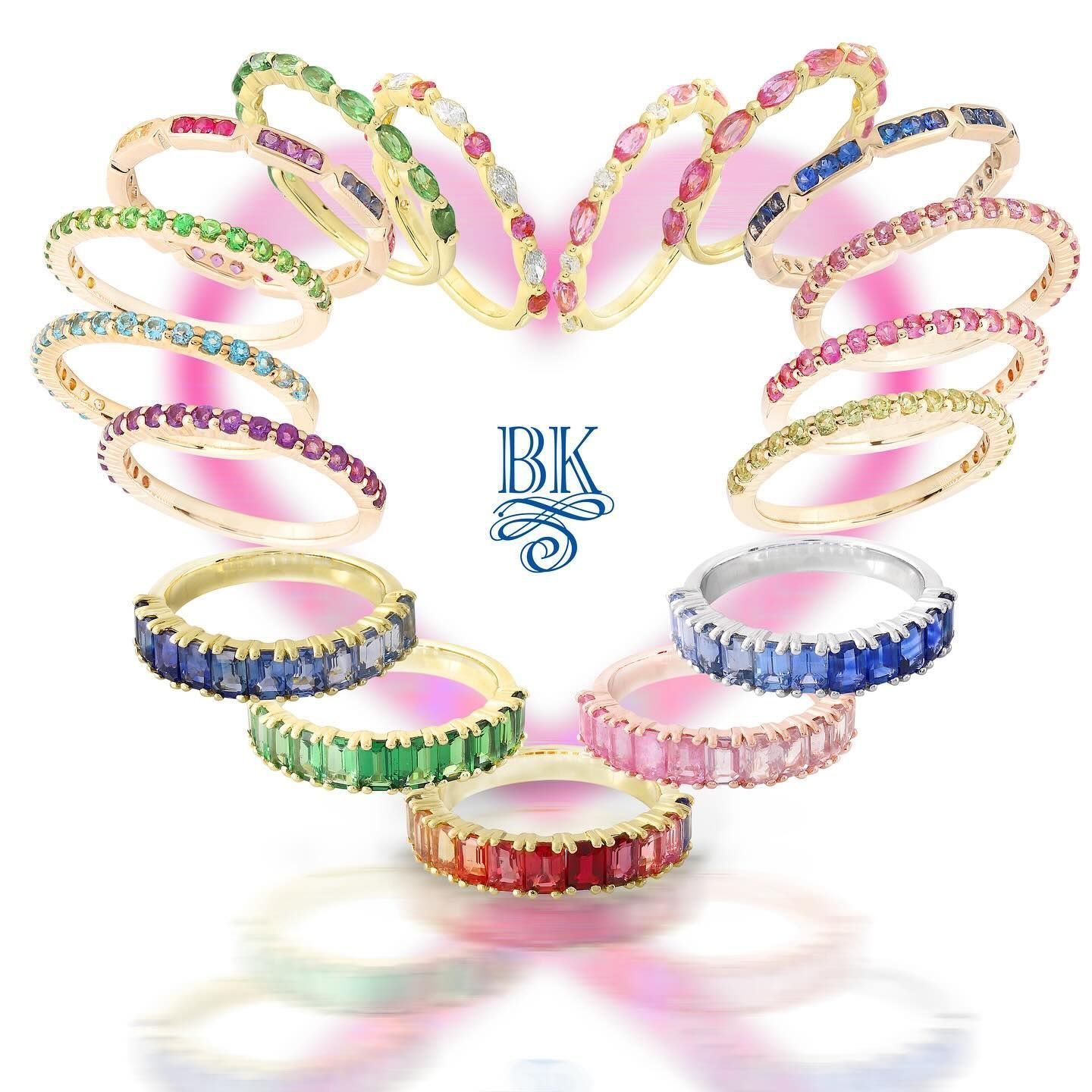 Colorful gemstone rings arranged in a heart shape against a white background.
