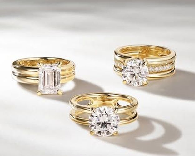 Three gold rings with diamonds, set on a white surface, with shadows.