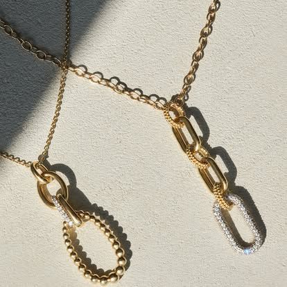 Two gold chain necklaces, one with a beaded oval pendant, the other with three chain links and a diamond-studded link.