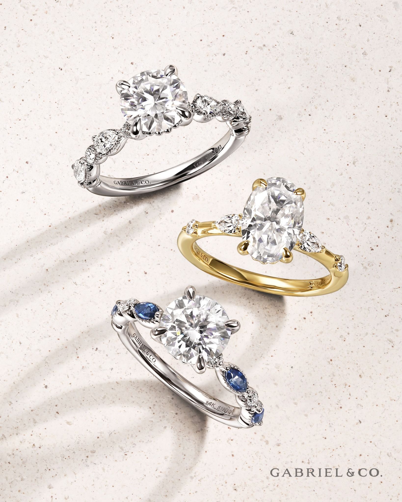 Three diamond engagement rings: white gold, yellow gold, and one with blue accents.