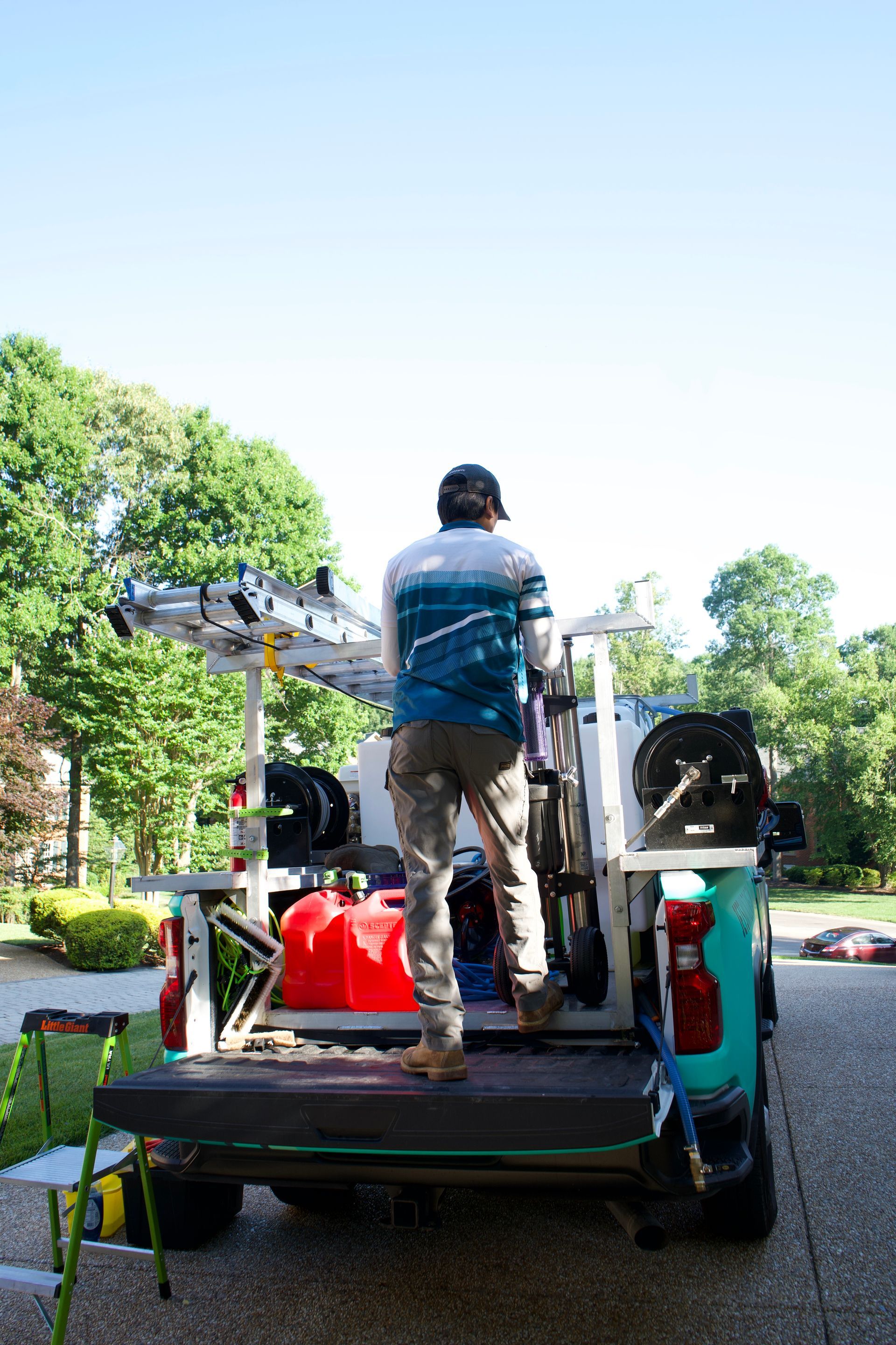 Person standing on a utility truck with equipment on a tree-lined street