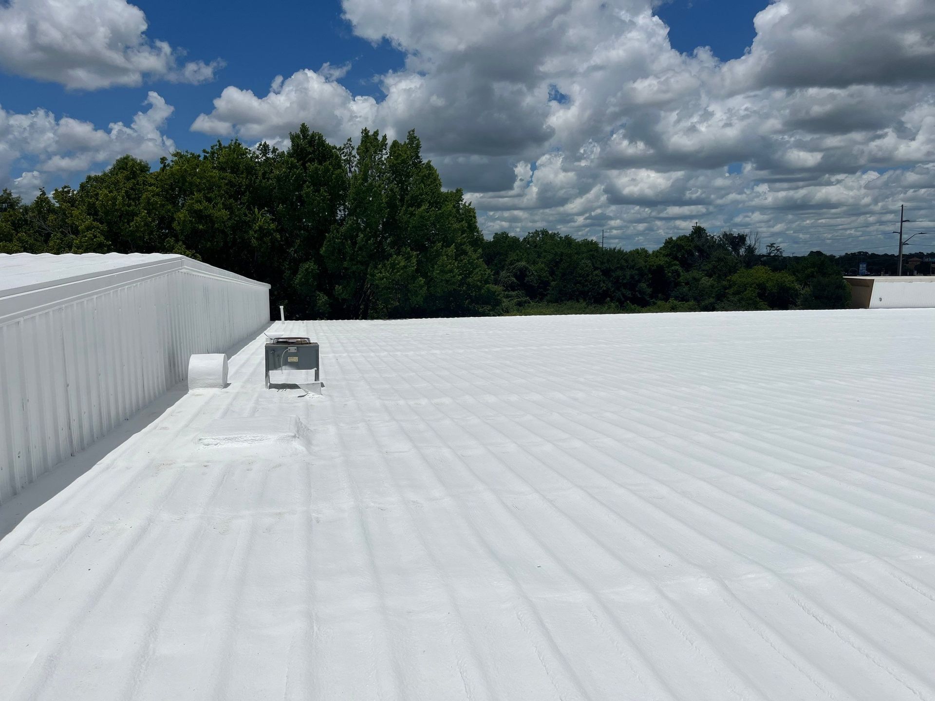 A white roof with a blue sky and clouds in the background.