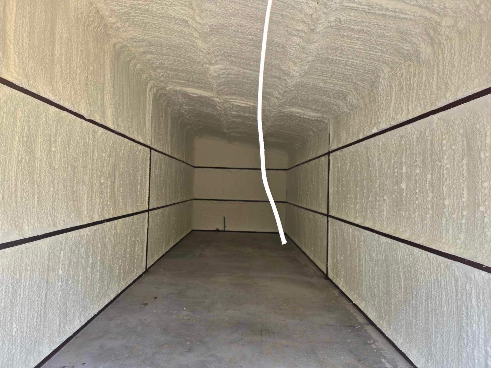 An empty room with a rope hanging from the ceiling.