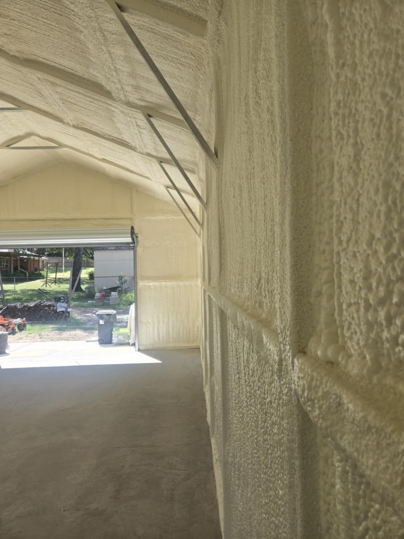 A garage with a door open and a wall covered in foam.