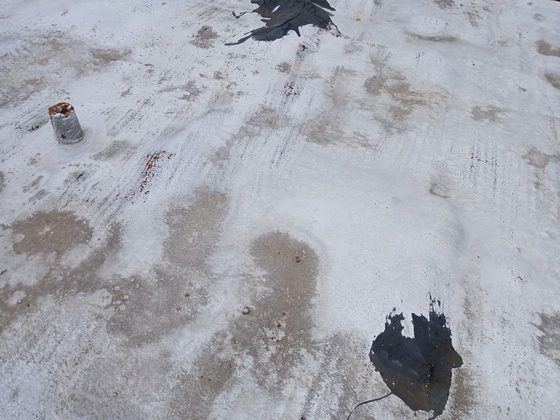 A dirty concrete surface with a few spots of black paint on it