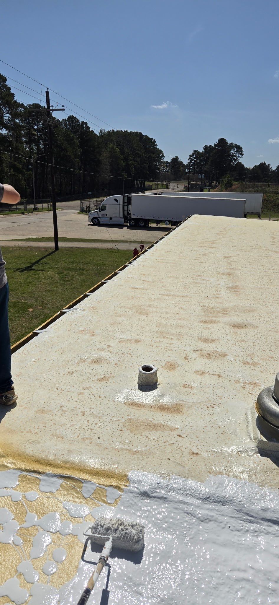 A man is standing on top of a roof with a truck in the background.