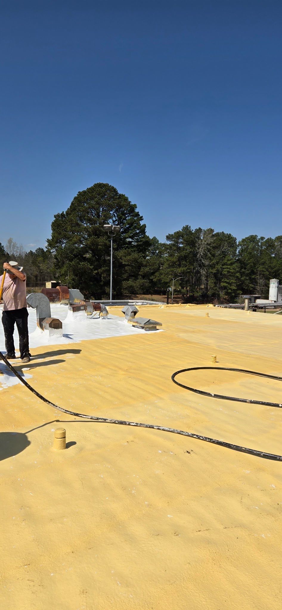 A man is standing on a roof with a hose.