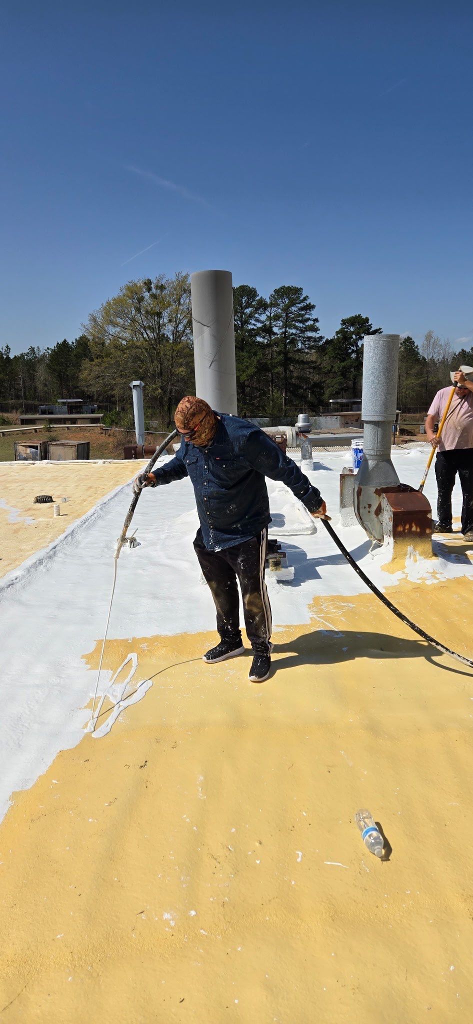 A man is painting a roof with a brush.