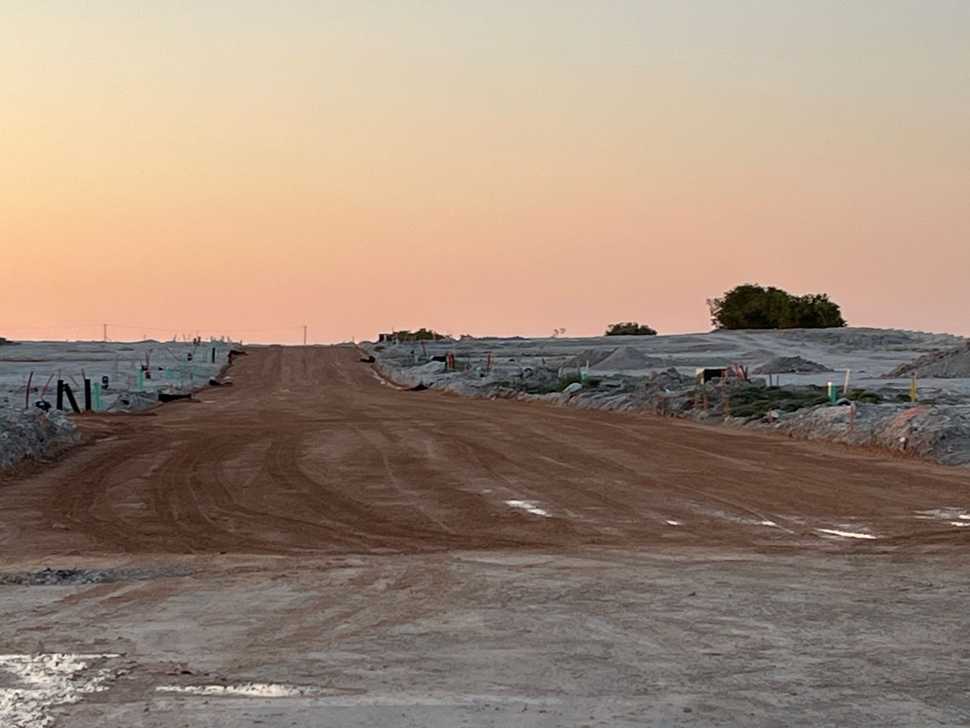 A dirt road with a sunset in the background.