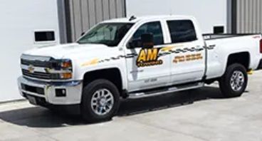 White AM Towing truck parked in front of a building.