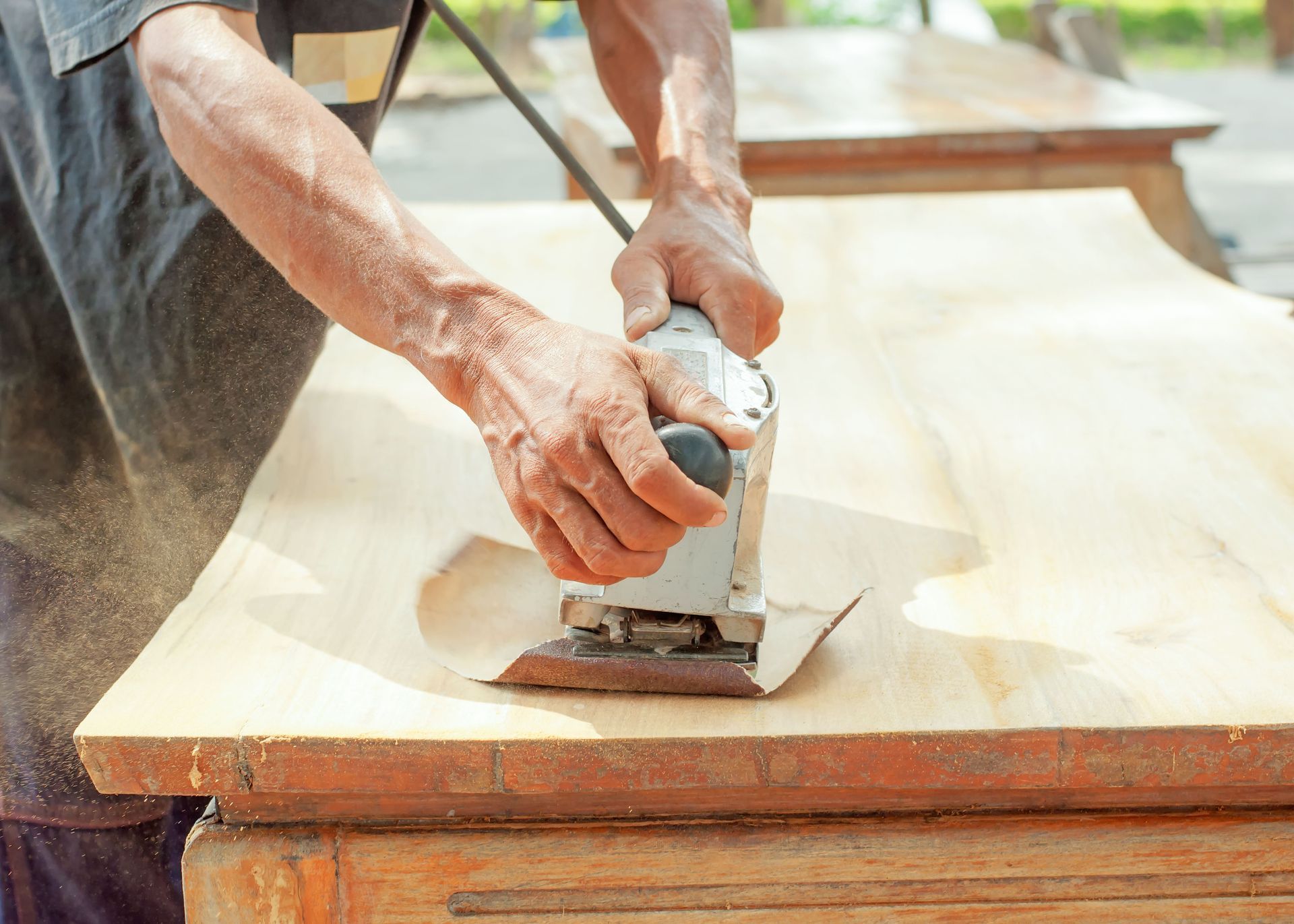 A man is sanding a piece of wood with a sander.