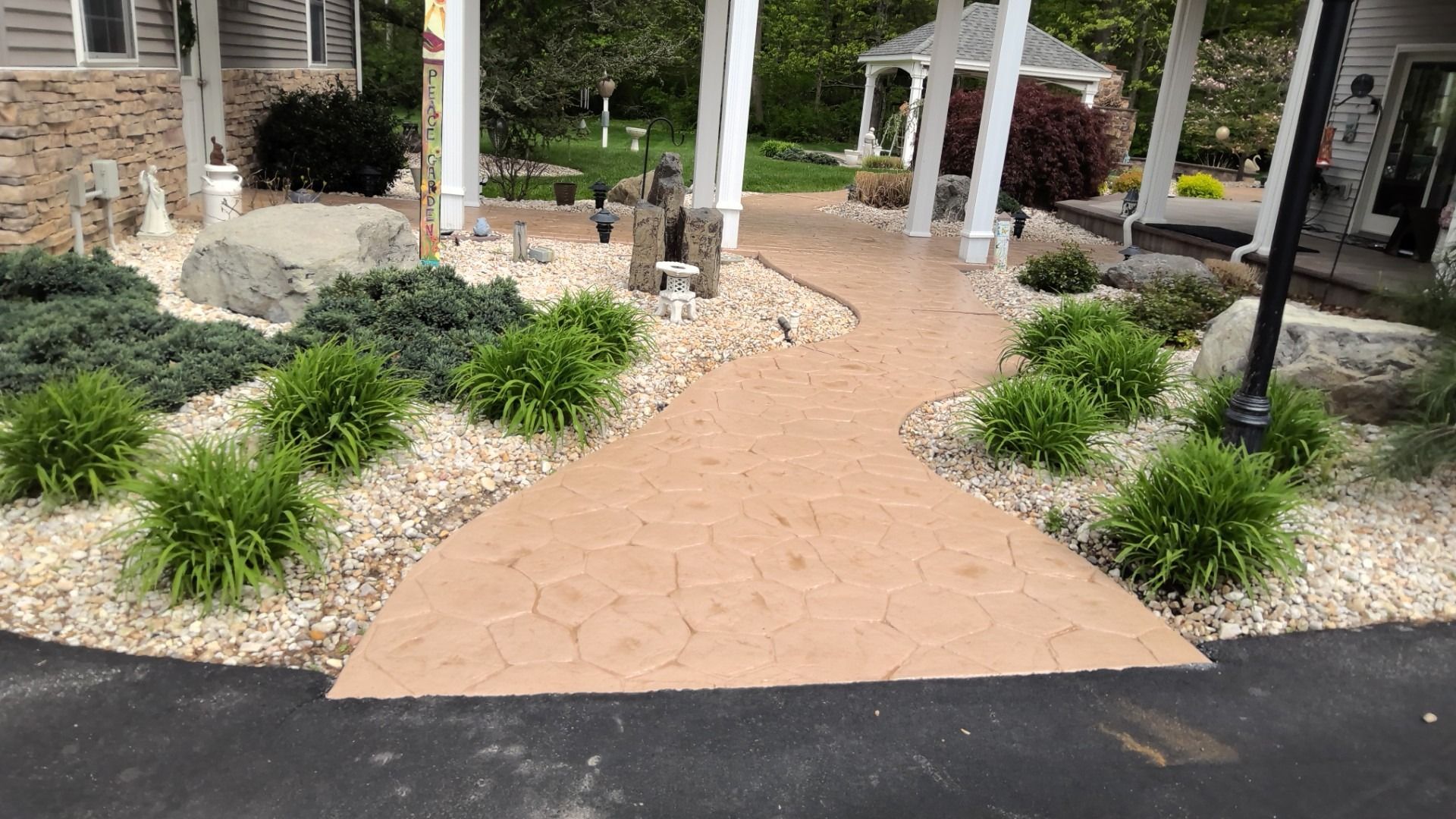 Brick walkway through landscaped garden to white pergola entrance