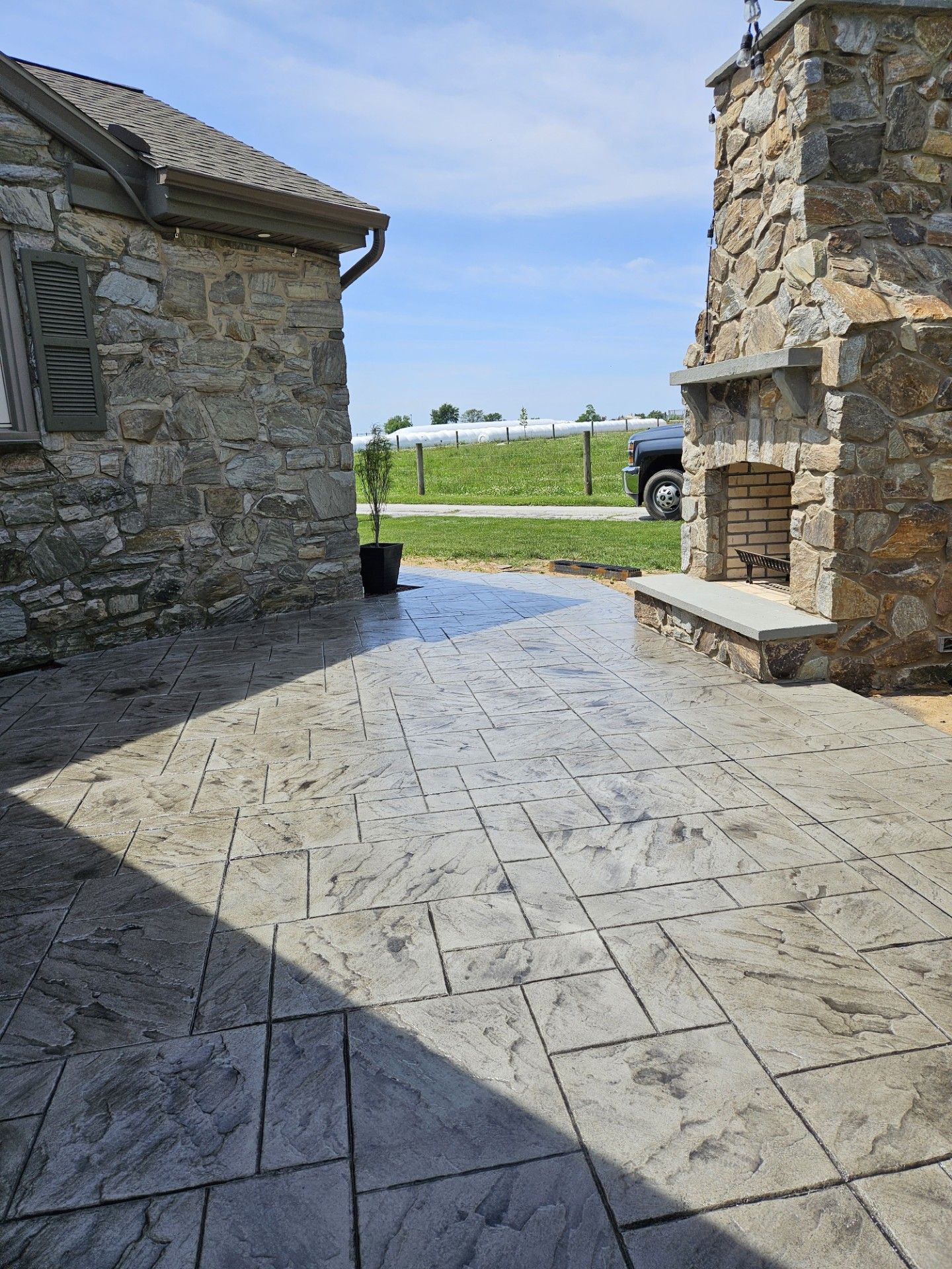 Stone courtyard between buildings, opening to a bright grassy landscape under a blue sky