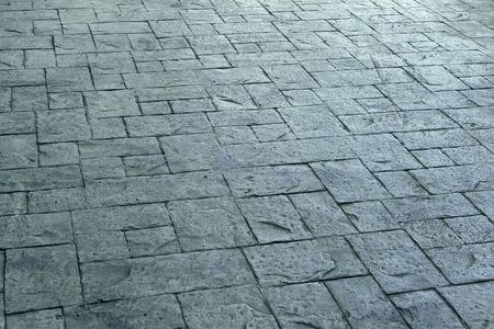 Textured, gray concrete patio with a brick pattern.