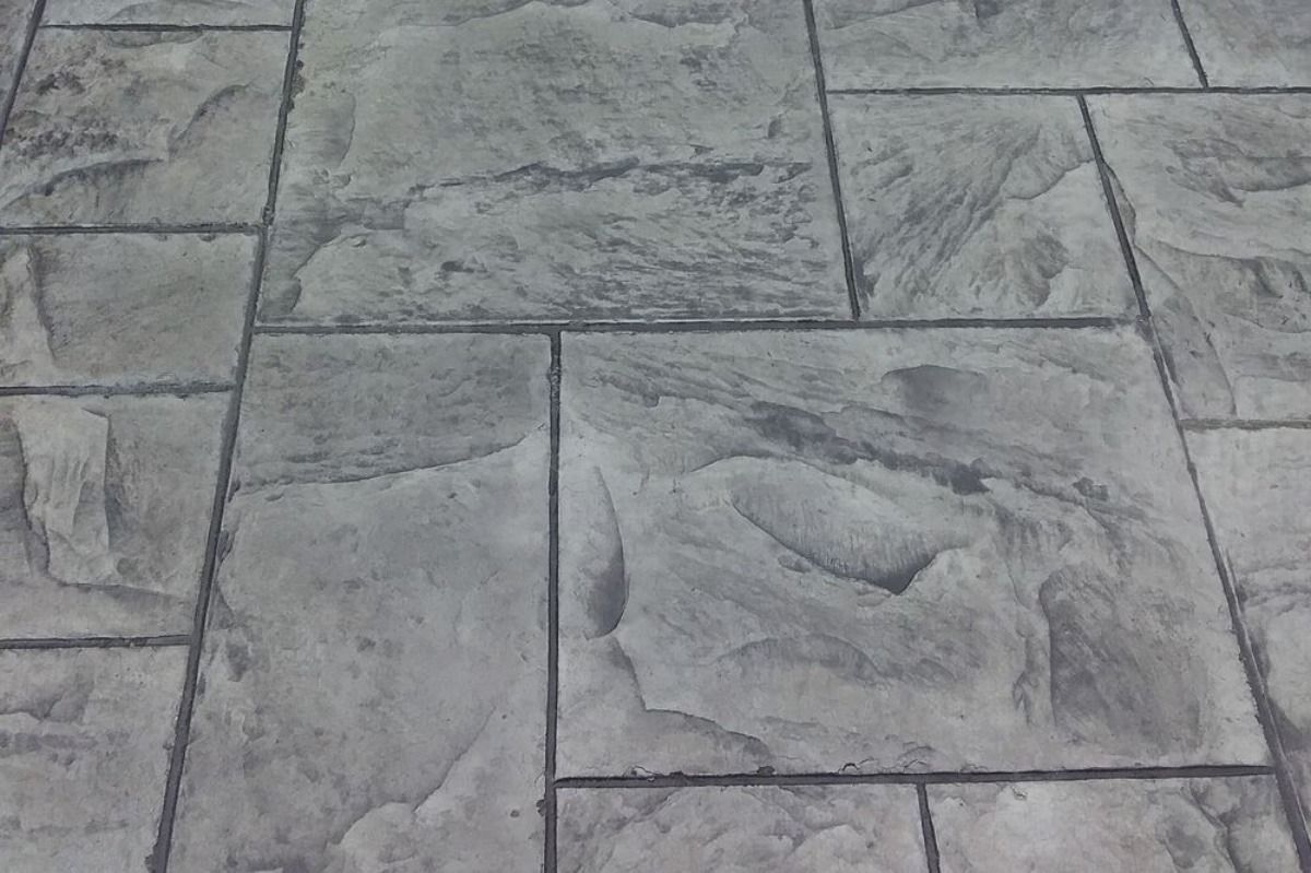 Gray stone patio with rectangular and square-shaped patterns, textured surface.