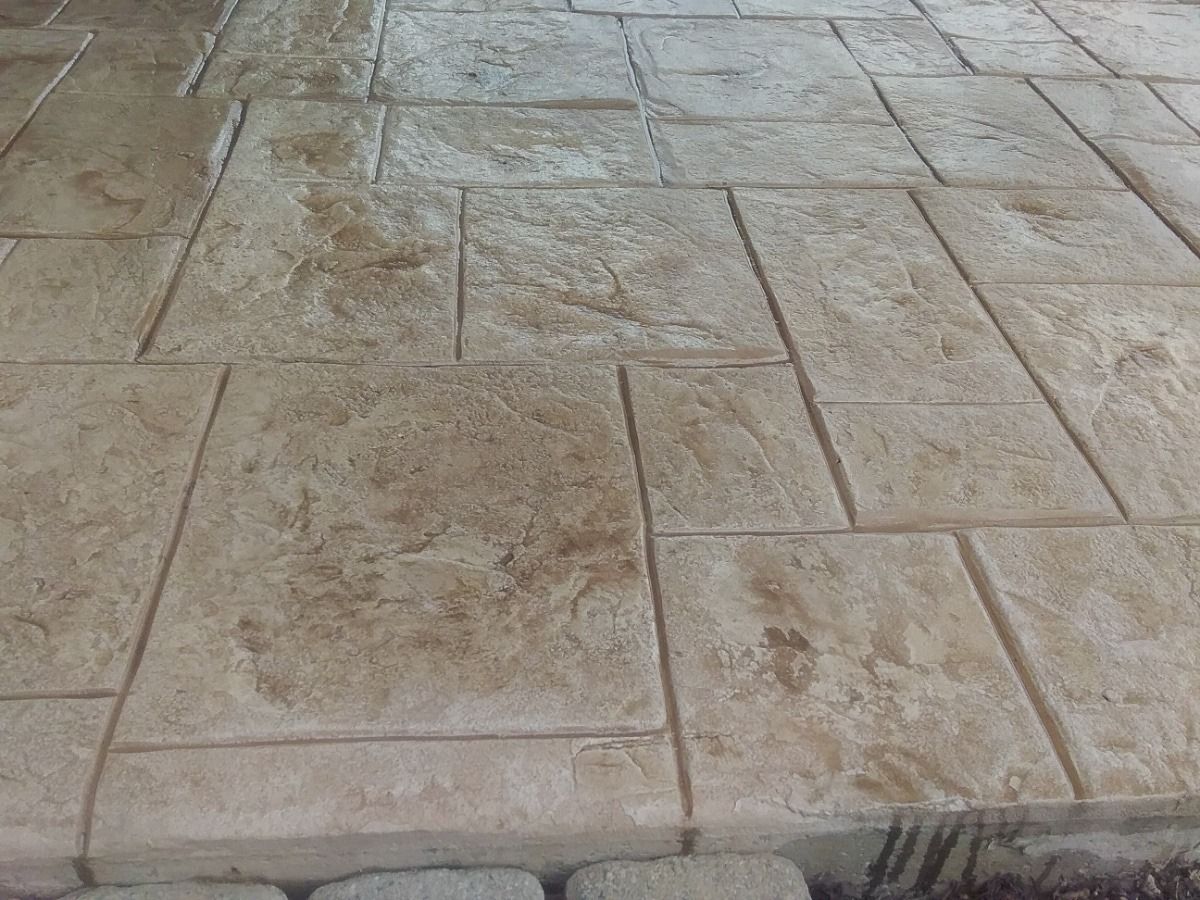 Beige stamped concrete patio with rectangular and square tile patterns.