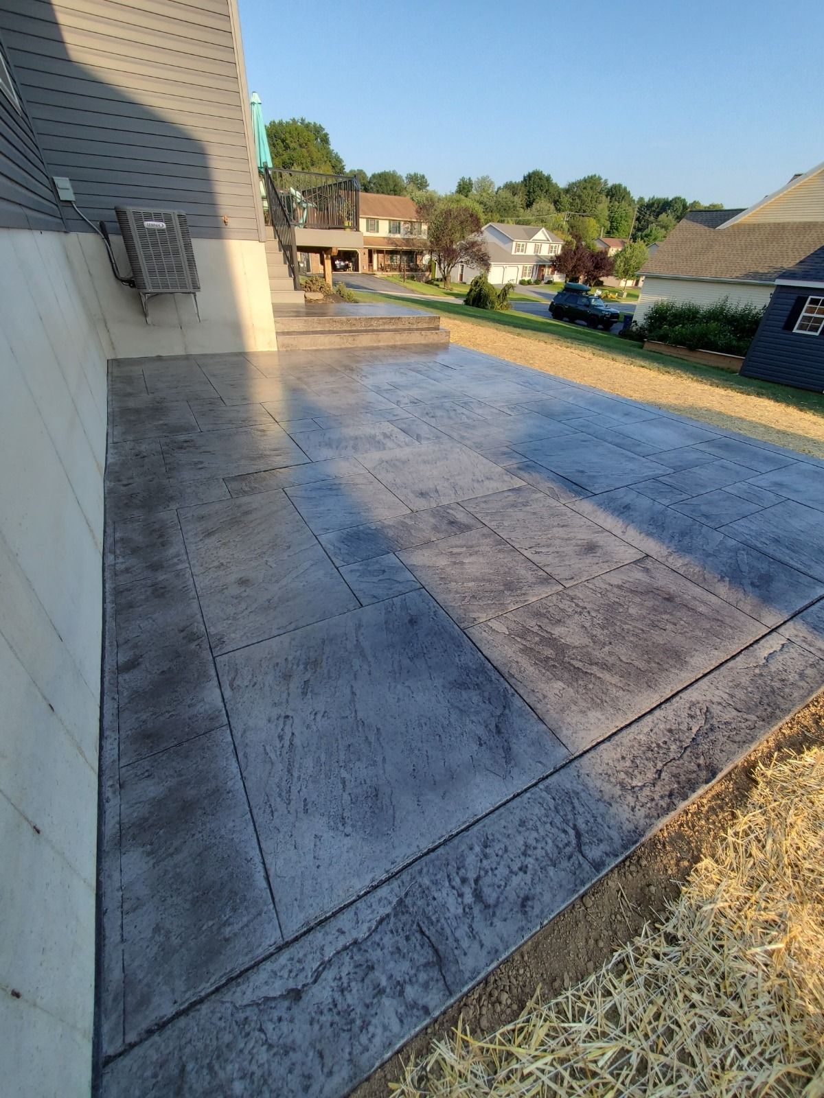 Stamped concrete patio next to a house. The patio is gray, with houses in the background.