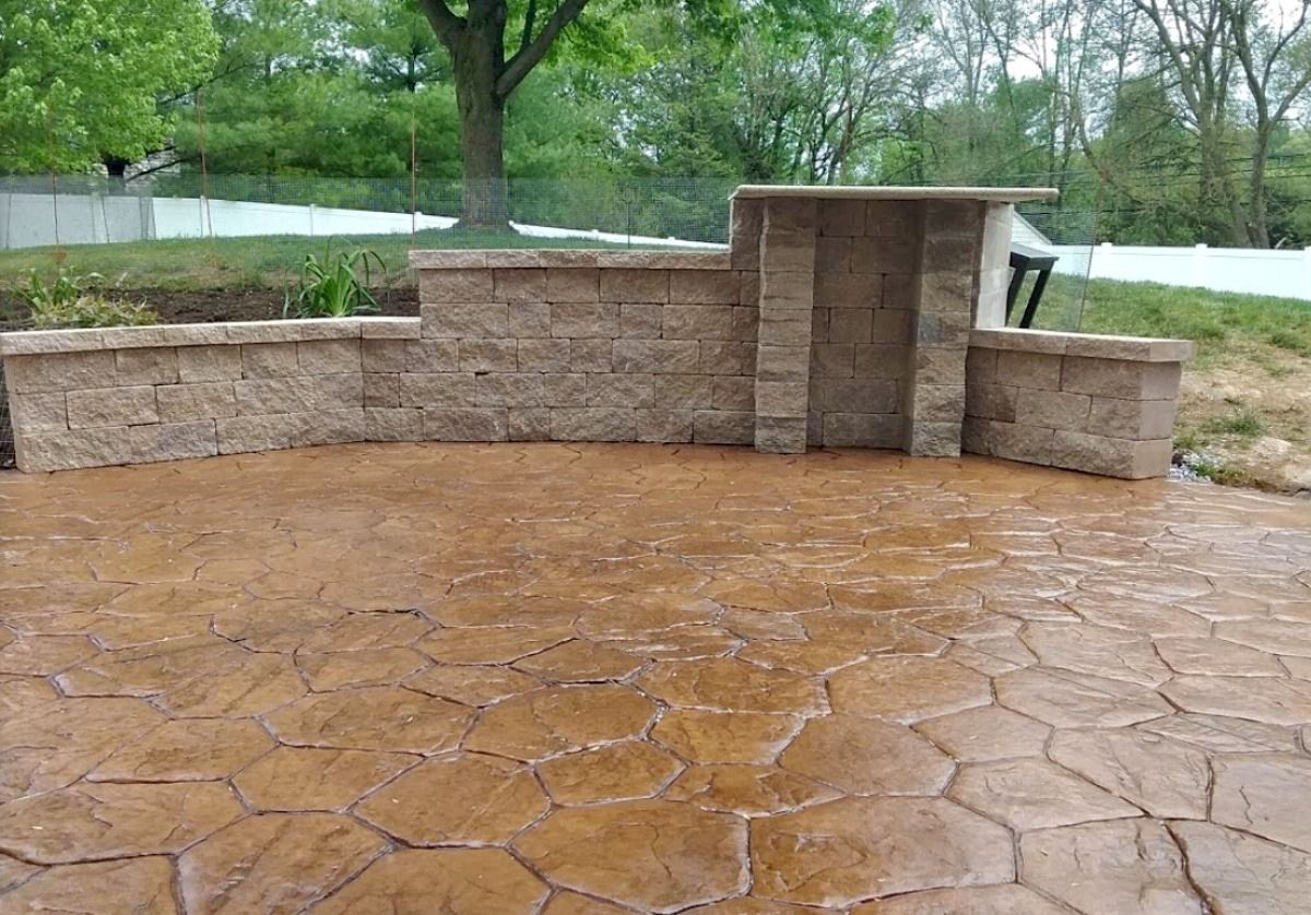 Brown stamped concrete patio with retaining walls, outdoor setting.