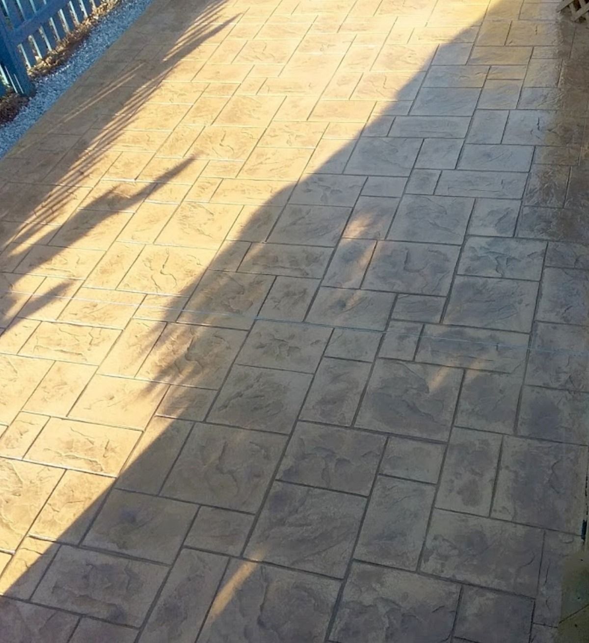 Stamped concrete patio with a shadow cast across it.