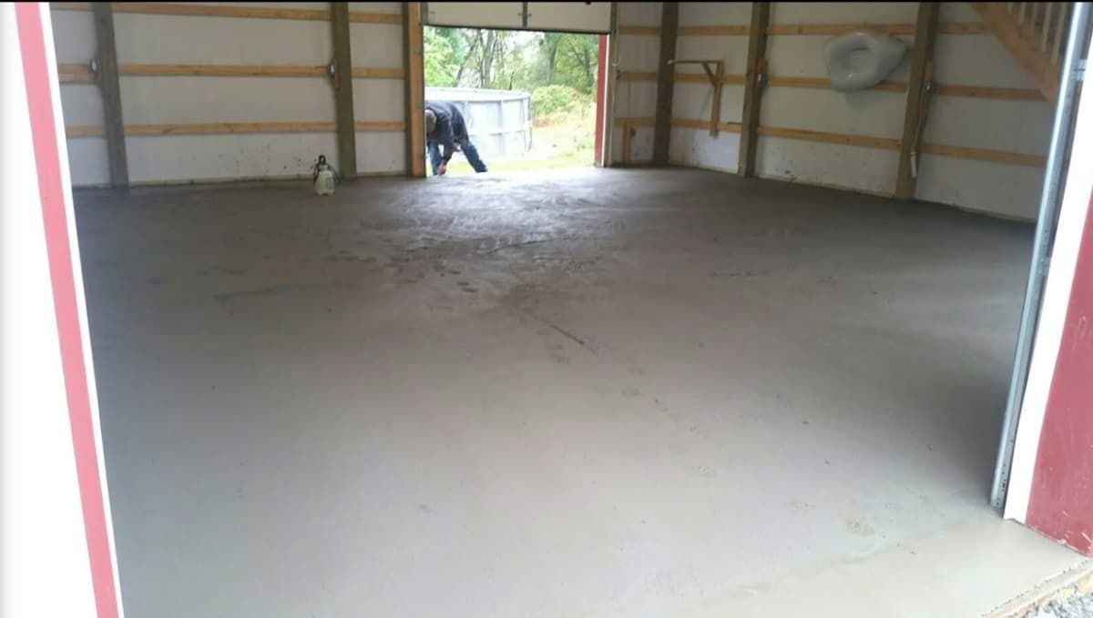 A new concrete floor inside a garage, with a person visible in the open doorway.