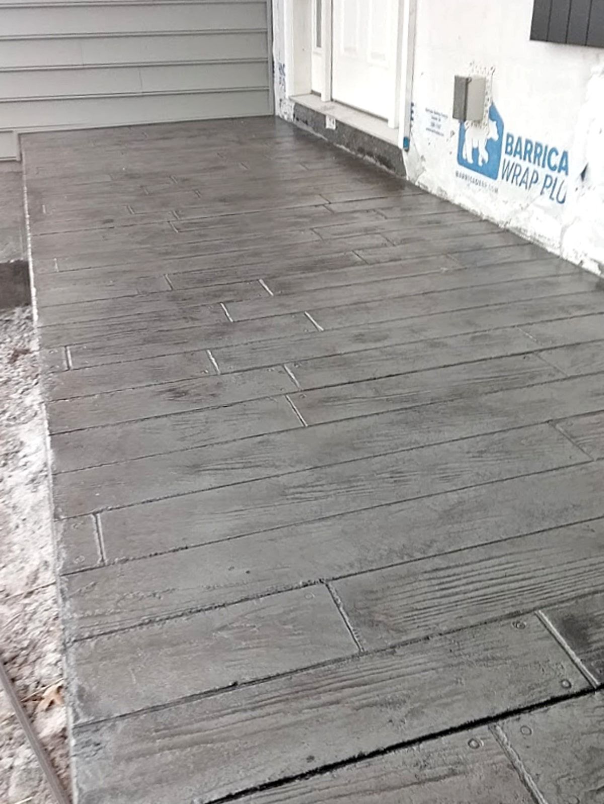 Concrete porch with gray wood plank pattern.