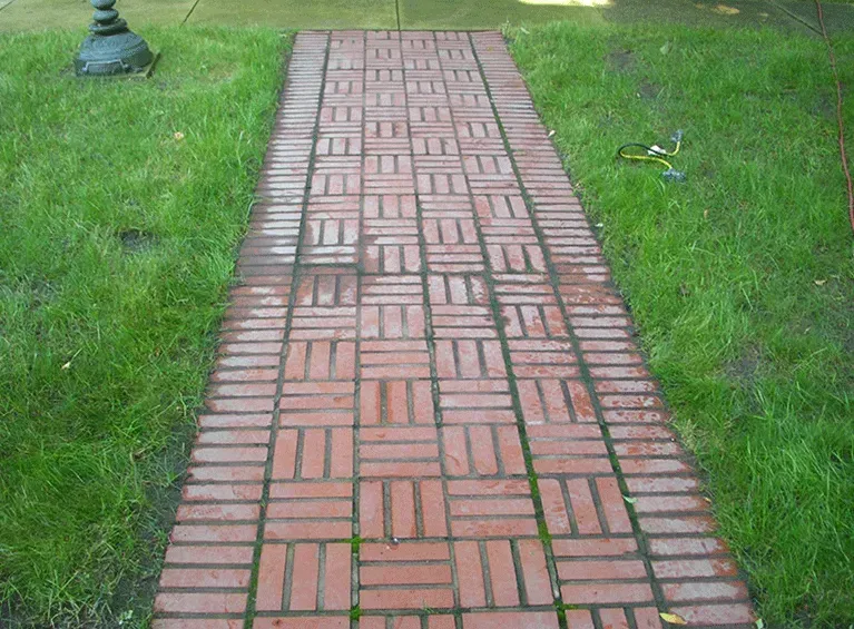 Brick walkway through green grass, with a lamp post on the left.