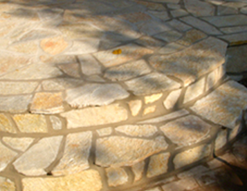 Curved stone steps made of irregular, tan-colored flagstones with mortar joints.