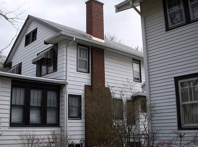 White two-story houses with black window frames and a prominent brick chimney exterior.