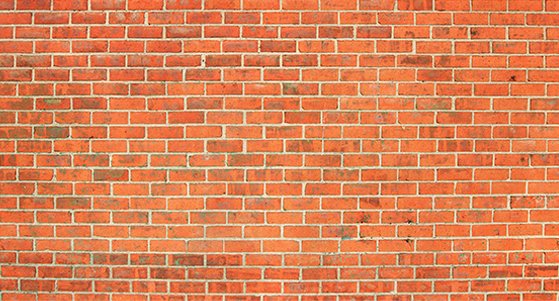 A wall constructed of uniform, rectangular red bricks arranged in a classic running bond pattern.