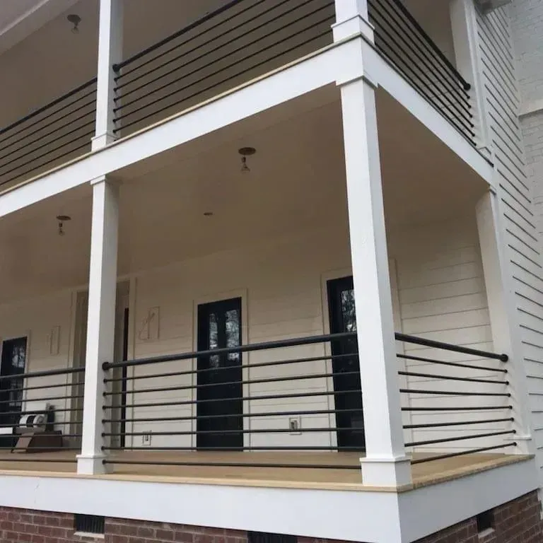 Two-story white house with black railings and doors. Porch has horizontal railings.