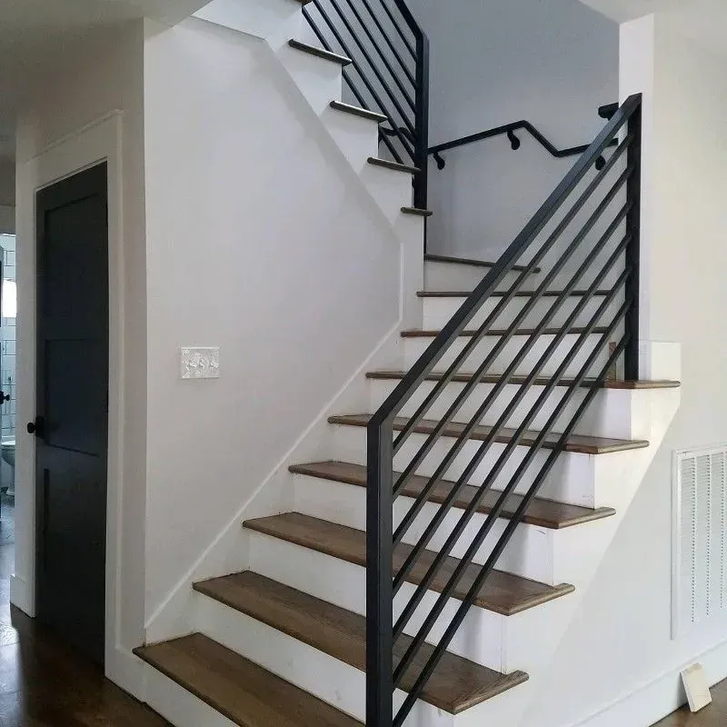 Staircase with wooden steps and black metal railings in a modern home.
