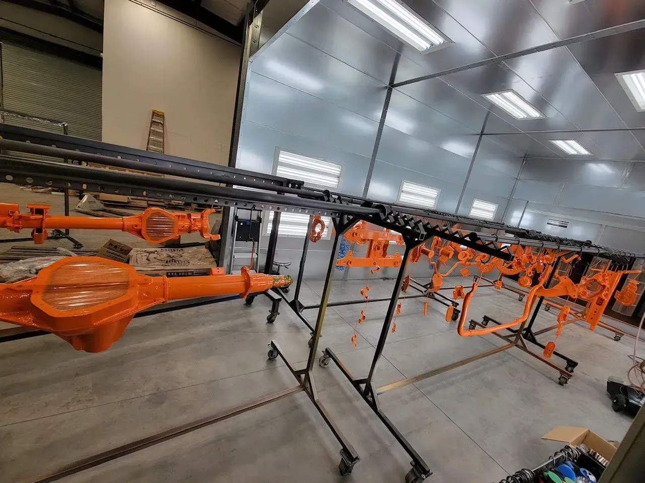 Orange car parts hanging on racks inside a workshop.