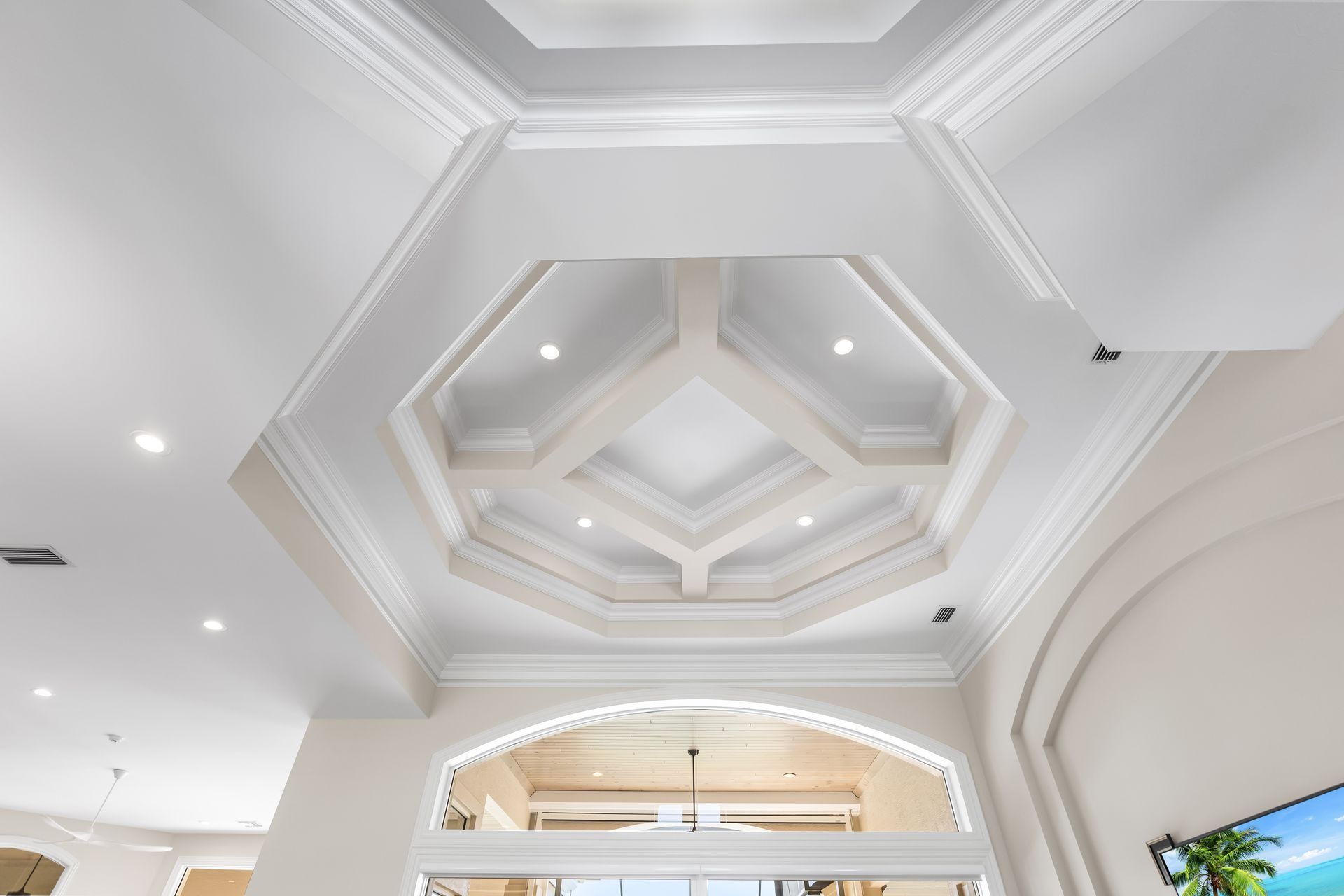 Ornate white ceiling with layered geometric design and recessed lighting.