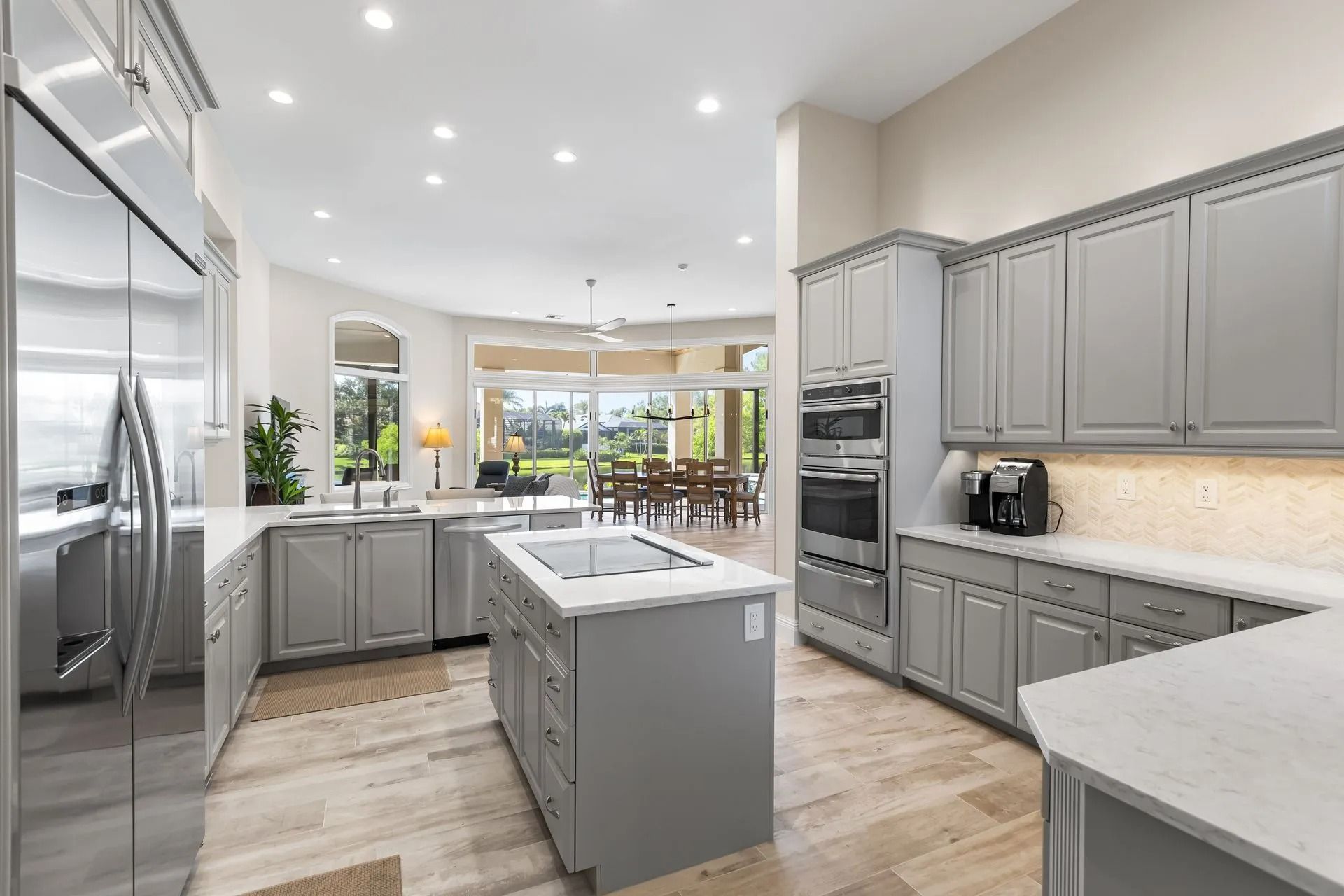 Modern gray kitchen with island, cabinets, appliances, and view to dining area.